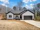 Charming, modern farmhouse with white siding, black trim, a front porch, and an attached garage at 619 Berkshire Dr, Statesville, NC 28677