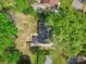 Aerial view of the house with a dark roof, a large lawn, and surrounded by mature trees and a white fence at 6813 Elm Forest Dr, Charlotte, NC 28212