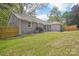 The backyard of the grey home has a lush lawn, wooden fence and mature trees at 6813 Elm Forest Dr, Charlotte, NC 28212