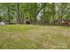 A fenced-in backyard features a green lawn, mature trees, and an outbuilding at 6813 Elm Forest Dr, Charlotte, NC 28212