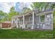 Charming gray brick home featuring a welcoming front porch with wooden railings, lush green lawn and manicured landscaping at 6813 Elm Forest Dr, Charlotte, NC 28212