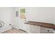 A laundry room features white walls and door with grey cabinets and light hardwood flooring at 6813 Elm Forest Dr, Charlotte, NC 28212