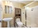 Compact yellow bathroom featuring a sink, toilet, cabinet, shower with glass doors, and vanity lights at 10349 Linksland Dr, Huntersville, NC 28078