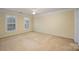 Spacious beige bedroom featuring a ceiling fan, two large windows, and neutral carpet flooring at 10349 Linksland Dr, Huntersville, NC 28078