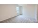 Simple bedroom with a large window and neutral colored carpet and walls at 116 Dorian Pl, Troutman, NC 28166