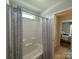 Well-lit bathroom featuring a tub with a shower curtain, connected to the main bedroom at 228 Heatherland Dr, Rock Hill, SC 29732