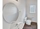 Well-lit half bathroom with a modern round mirror and a white sink and toilet at 246 Tail Race Ln, Fort Mill, SC 29715