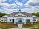 Stunning clubhouse exterior featuring white columns, stone accents and ample windows, set against a bright sky at 2617 Manor Stone Way, Indian Trail, NC 28079