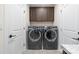 Modern laundry room equipped with front-load washer and dryer, plus sleek dark wood cabinetry at 305 Hemlock Bluff Ct, Denver, NC 28037