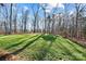Expansive green lawn surrounded by mature trees, offering a serene and private backyard setting at 324 Patternote Rd, Mooresville, NC 28117