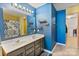 Modern bathroom featuring a dual sink vanity, floating shelves, and blue accent wall at 3247 Bamburgh Ct, Charlotte, NC 28216