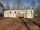 Exterior elevation of mobile home with a wooden deck and siding, nestled among trees and foliage at 335 Lake Landing Dr, Salisbury, NC 28146