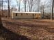 View of the mobile home exterior featuring a well-lit view and a wooden deck amidst a wooded landscape at 335 Lake Landing Dr, Salisbury, NC 28146