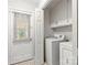 A well-lit laundry room featuring a washer, dryer, overhead cabinets, and a door to the outside at 410 Deerwood Dr, Gastonia, NC 28054