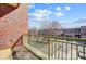 A view of a parking lot and the street from a balcony with a green railing and brick walls at 720 Governor Morrison St # 207, Charlotte, NC 28211
