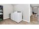 Functional laundry area with a washer, dryer, shelving, and seamless wood-look flooring at 805 Deep River Way, Waxhaw, NC 28173