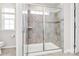 Modern shower features glass door, neutral tile, built in seat, and a convenient hand-held shower head at 805 Deep River Way, Waxhaw, NC 28173