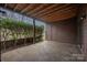 Covered patio with wood ceiling, privacy bushes, and door to storage room offers outdoor living at 8057 Cedar Glen Dr, Charlotte, NC 28212