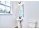 Powder room with pedestal sink and toilet, natural light from the window at 107 Megby Trl, Statesville, NC 28677