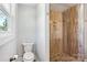 Half bathroom features a toilet and a glass enclosed walk-in shower with tiled walls and pebble floor at 14325 Rocky River E Rd, Davidson, NC 28036