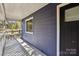 A covered porch with gray decking and white railings next to a black front door for a contemporary feel at 14325 Rocky River E Rd, Davidson, NC 28036