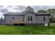 Rear exterior of a gray home with a wooden deck, small basement entrance, and a lush, green lawn at 203 S Hill Ave # 3, Albemarle, NC 28001