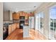 Well-lit kitchen with wood cabinets, hardwood floors, stainless steel refrigerator, and functional island at 9724 Walkers Glen Nw Dr, Concord, NC 28027