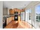 Sun-filled kitchen featuring stainless steel refrigerator, wood cabinets, hardwood floors, and sliding glass doors at 9724 Walkers Glen Nw Dr, Concord, NC 28027