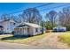 Charming single-story home with a screened-in porch and a detached garage, surrounded by mature trees and a blue sky at 102 Fire Department Dr, Belmont, NC 28012