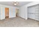 Bright bedroom with ceiling fan, carpet floors, and closet with shelving unit at 11020 Carmel Crossing Rd, Charlotte, NC 28226