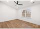 A well lit bedroom featuring hardwood floors, ceiling fan, and a large window at 130 Valley Glen Dr, Troutman, NC 28166