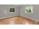 An empty bedroom with two windows overlooking trees and hardwood floors at 141 Baywatch Dr, Mooresville, NC 28117