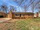 Charming brick home featuring mature landscaping and a classic chimney, set under a blue sky at 207 Bright Ave, Bessemer City, NC 28016