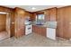 The kitchen features wood cabinets, a window view, and sleek white appliances against a neutral floor at 207 Bright Ave, Bessemer City, NC 28016