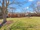 A large tree graces the spacious backyard, which features a brick home, wooden deck, and carport at 3204 Starrland Dr, Gastonia, NC 28052