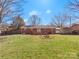 An expansive backyard featuring a brick home, wooden deck, and carport, ideal for outdoor activities at 3204 Starrland Dr, Gastonia, NC 28052