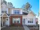Charming two-story townhome featuring brick accents, white siding, and blue shutters. The front door features a spring themed wreath at 7725 Petrea Ln, Charlotte, NC 28227