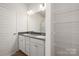 Well-lit bathroom featuring a double vanity, a shower, and shelving unit for storage solutions at 8109 Jacey Ln # 40, Huntersville, NC 28078
