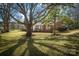 Charming brick home with lush front yard and mature trees casting dappled shadows on a sunny day at 924 S Main Ave, Newton, NC 28658