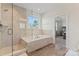 Bright bathroom featuring tiled shower, soaking tub beneath a window, and wood-look tile flooring at 12018 Grey Partridge Dr, Charlotte, NC 28278