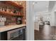 Butler pantry with brick accent wall, floating shelves, countertop, and under-counter beverage refrigerator at 12018 Grey Partridge Dr, Charlotte, NC 28278