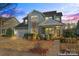 Charming two-story home with light blue siding, a manicured front yard, and inviting front porch at dusk at 12018 Grey Partridge Dr, Charlotte, NC 28278