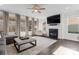 Cozy living room with a fireplace, mantle, dark hardwood floors, a ceiling fan, and large windows at 12018 Grey Partridge Dr, Charlotte, NC 28278