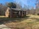 Charming brick home with a cozy front porch and mature trees in a partially overgrown yard at 128 Trexler Ave, Mount Holly, NC 28120