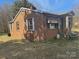 Charming brick home with a cozy front porch and mature trees in a partially overgrown yard at 128 Trexler Ave, Mount Holly, NC 28120