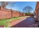Open backyard with brick fence, mature tree, and patio perfect for outdoor activities at 1910 Connemara Ct, Gastonia, NC 28054