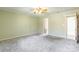 Comfortable bedroom with neutral carpet, ceiling fan, light green walls, and wood-grain door at 1910 Connemara Ct, Gastonia, NC 28054