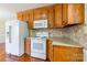 This kitchen includes wood cabinetry, tiled backsplash, white refrigerator, microwave, and stove at 1910 Connemara Ct, Gastonia, NC 28054