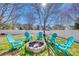 Backyard with a fire pit circled by bright blue Adirondack chairs beneath a beautiful shade tree at 249 Sand Paver Way, Fort Mill, SC 29708