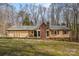 Ranch home featuring a brick chimney and covered front porch set amidst a tree-lined landscape at 285 Straightaway Ln, Indian Land, SC 29707